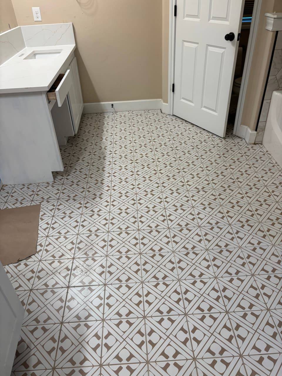 Patterned tile floor in a remodeled bathroom with a new vanity and door